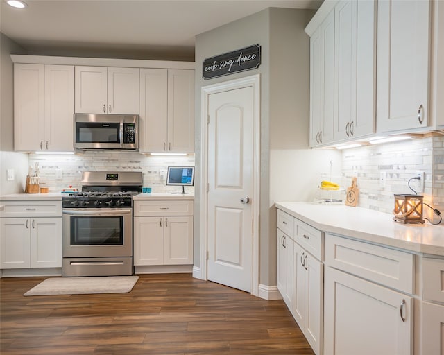 kitchen with stainless steel appliances, white cabinets, dark wood-type flooring, and decorative backsplash