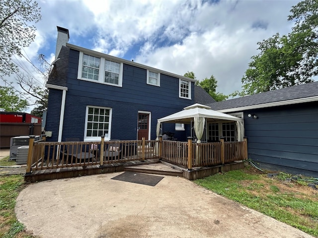 back of property featuring central AC, a wooden deck, a patio, a chimney, and a gazebo