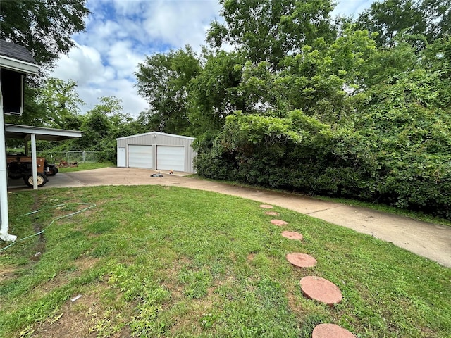 view of yard with a detached garage, fence, and an outdoor structure