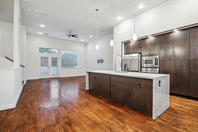 kitchen featuring appliances with stainless steel finishes, a kitchen island with sink, ceiling fan, decorative light fixtures, and dark hardwood / wood-style floors