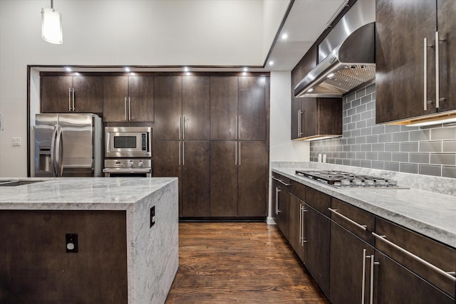 kitchen with pendant lighting, wall chimney range hood, dark hardwood / wood-style floors, appliances with stainless steel finishes, and dark brown cabinetry