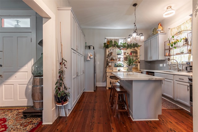 kitchen featuring decorative backsplash, dark wood-type flooring, a center island, and sink