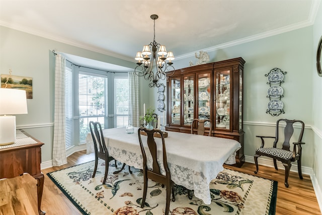 dining space featuring crown molding, a notable chandelier, and light hardwood / wood-style flooring