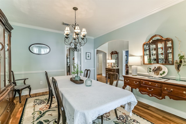 dining area with an inviting chandelier, crown molding, and light hardwood / wood-style floors