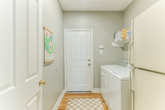 laundry area with washer and clothes dryer and light wood-type flooring