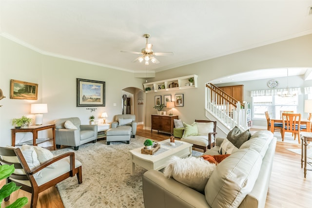 living room featuring light hardwood / wood-style flooring, ornamental molding, and ceiling fan with notable chandelier