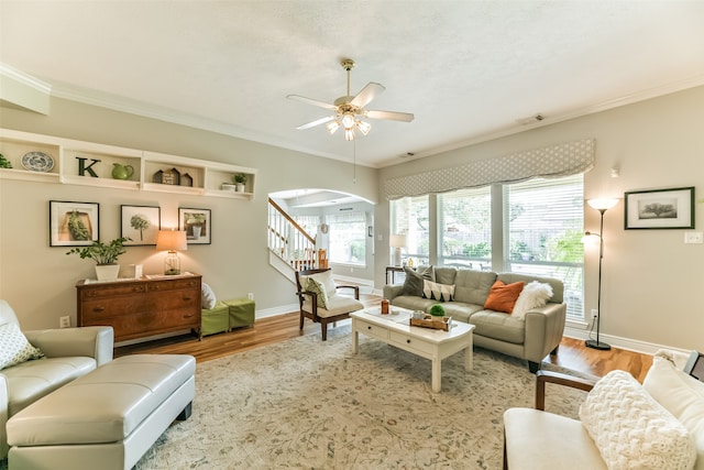 living room with ornamental molding, wood-type flooring, and ceiling fan