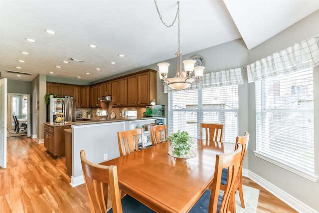 dining room with light wood-type flooring, a chandelier, and plenty of natural light