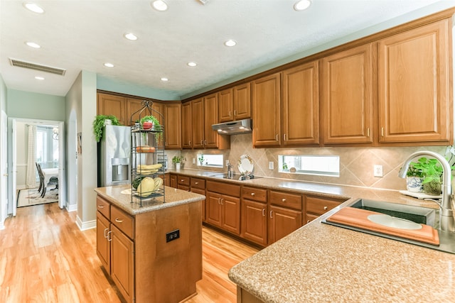 kitchen featuring sink, light hardwood / wood-style floors, a center island, and backsplash