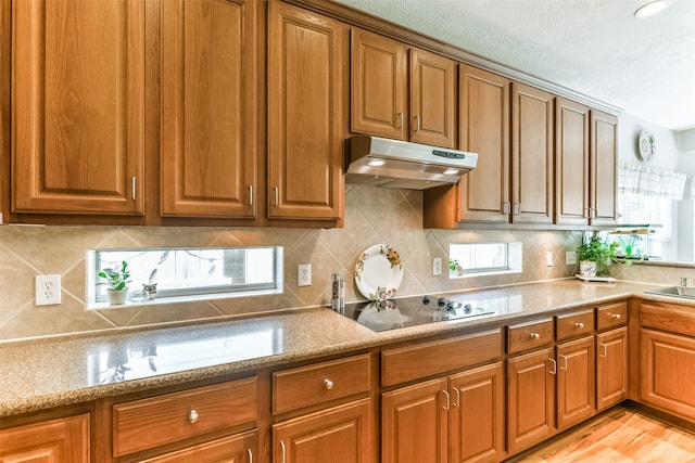 kitchen featuring plenty of natural light, decorative backsplash, light hardwood / wood-style floors, and black electric cooktop