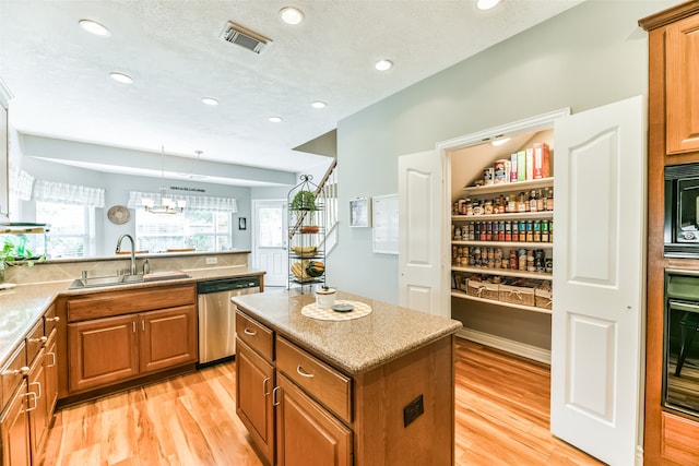 kitchen with light hardwood / wood-style flooring, sink, a center island, black appliances, and a textured ceiling