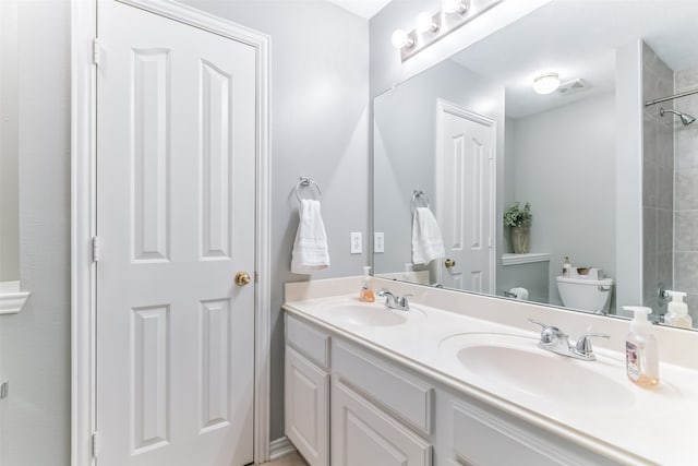 bathroom with toilet, vanity, and a tile shower