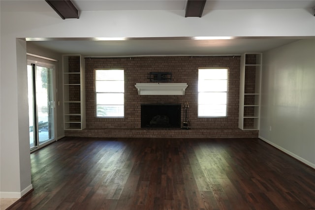 unfurnished living room with beam ceiling, a fireplace, brick wall, and dark hardwood / wood-style floors