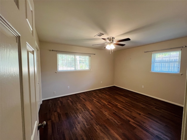 spare room with a wealth of natural light, dark hardwood / wood-style floors, and ceiling fan