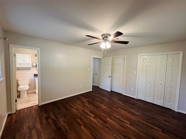 unfurnished bedroom with dark hardwood / wood-style flooring, ensuite bathroom, two closets, and ceiling fan