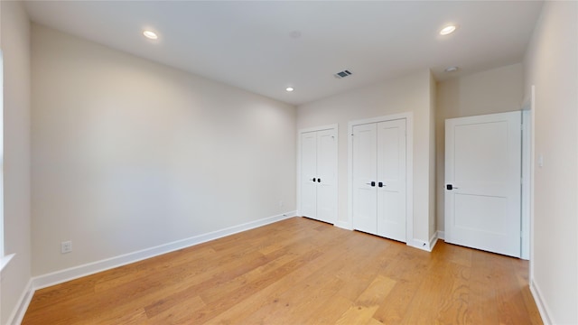 unfurnished bedroom featuring light hardwood / wood-style floors and multiple closets