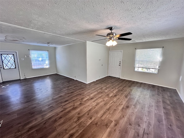 unfurnished living room with dark wood-type flooring, a textured ceiling, and plenty of natural light