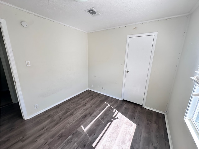 spare room featuring a textured ceiling and dark hardwood / wood-style flooring