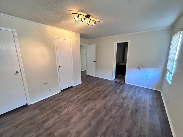 unfurnished bedroom featuring ornamental molding, a textured ceiling, ensuite bath, and dark wood-type flooring