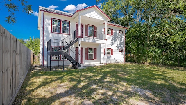 rear view of property with a yard and a balcony