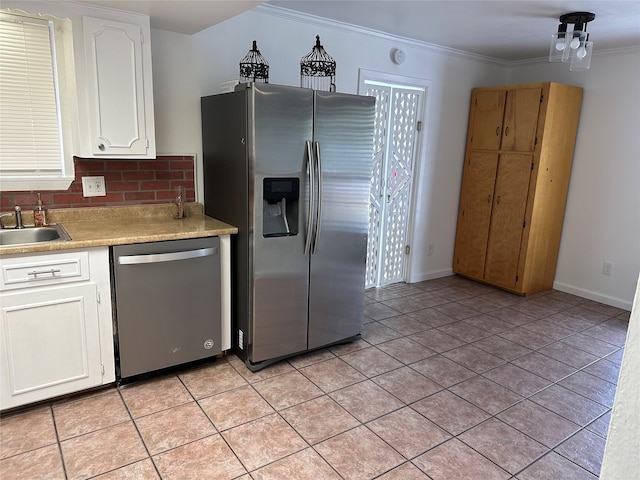 kitchen featuring sink, light tile patterned flooring, white cabinetry, stainless steel appliances, and ornamental molding