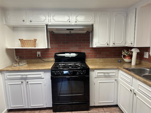 kitchen with black gas range, white cabinets, light tile patterned flooring, and tasteful backsplash