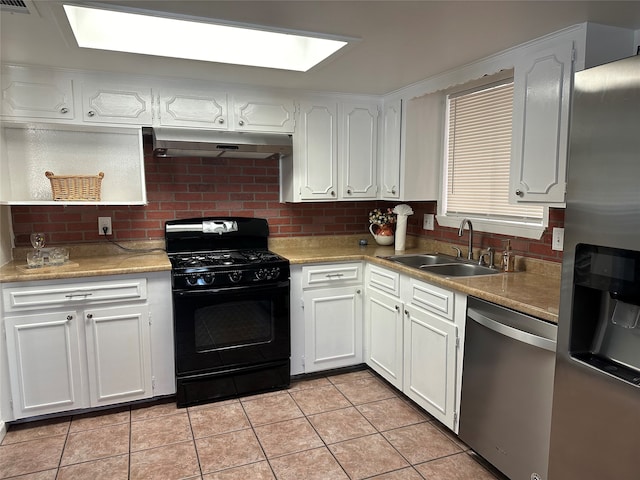 kitchen with tasteful backsplash, appliances with stainless steel finishes, light tile patterned flooring, sink, and white cabinets