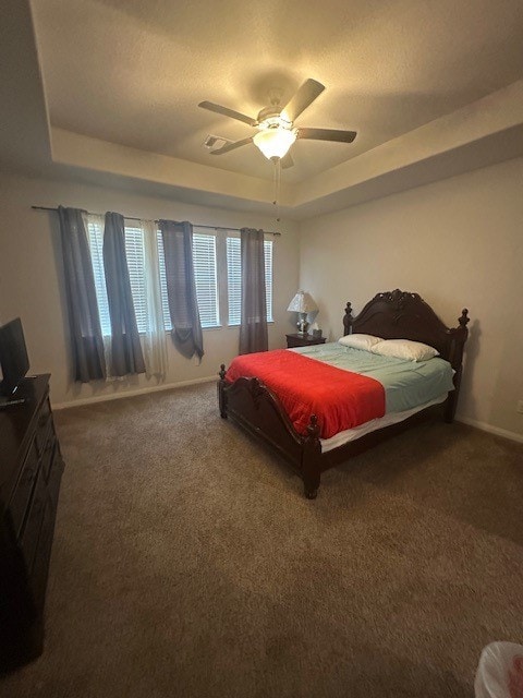 bedroom featuring ceiling fan, a raised ceiling, and carpet flooring