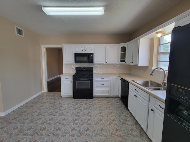 kitchen with sink, black appliances, white cabinetry, and tasteful backsplash