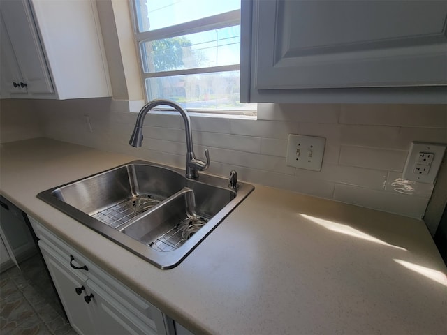 kitchen with white cabinetry, backsplash, and sink