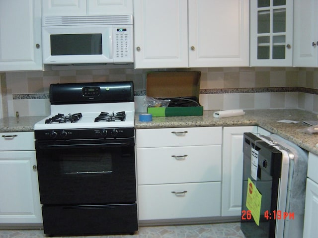 2601 Wheeler St, Houston, TX 77004 - kitchen with range with gas cooktop, white microwave, white cabinets, and backsplash