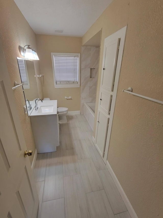 2601 Wheeler St, Houston, TX 77004 - bathroom with toilet, a textured wall, vanity, tub / shower combination, and baseboards