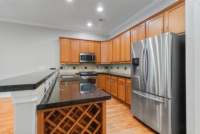 kitchen with kitchen peninsula, sink, crown molding, light wood-type flooring, and appliances with stainless steel finishes