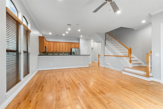 unfurnished living room featuring ornamental molding, light wood-type flooring, and ceiling fan