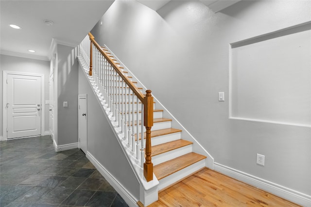 stairs with crown molding and wood-type flooring