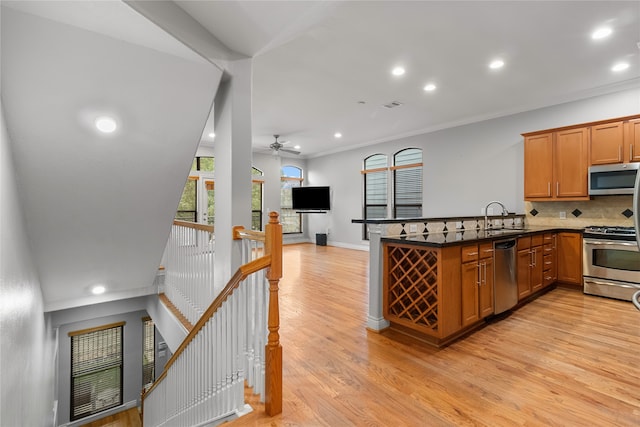 kitchen featuring kitchen peninsula, tasteful backsplash, light hardwood / wood-style flooring, sink, and stainless steel appliances