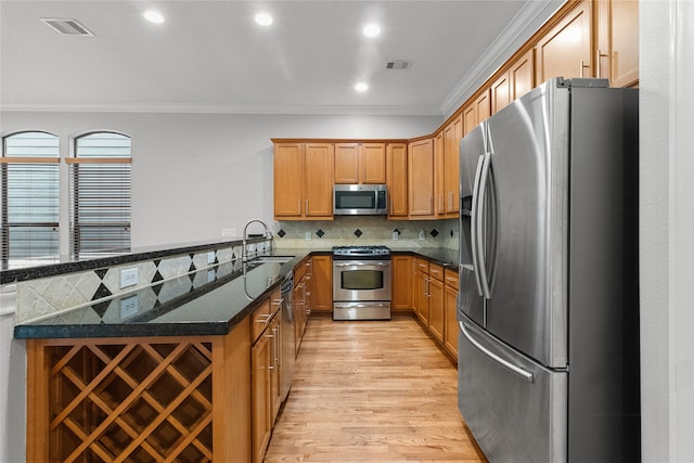 kitchen featuring dark stone counters, light wood-type flooring, ornamental molding, sink, and stainless steel appliances