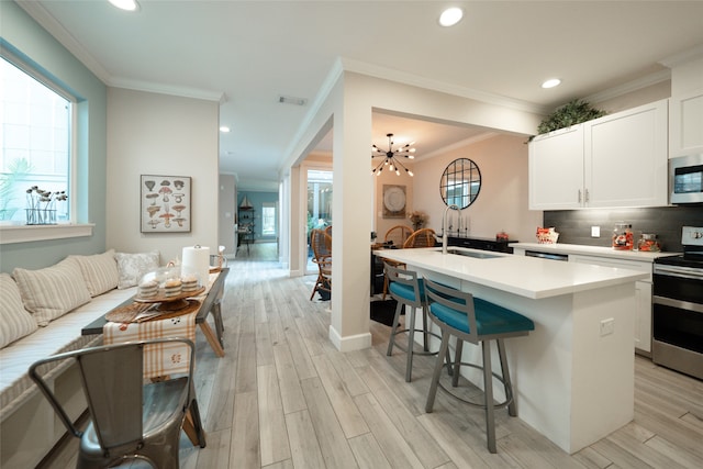 kitchen featuring a healthy amount of sunlight, stainless steel appliances, sink, and an island with sink