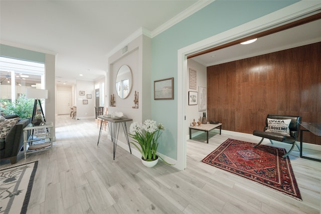 hallway with ornamental molding, wooden walls, and light wood-type flooring