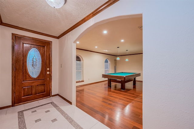 foyer entrance with crown molding, pool table, a textured ceiling, and light wood-type flooring