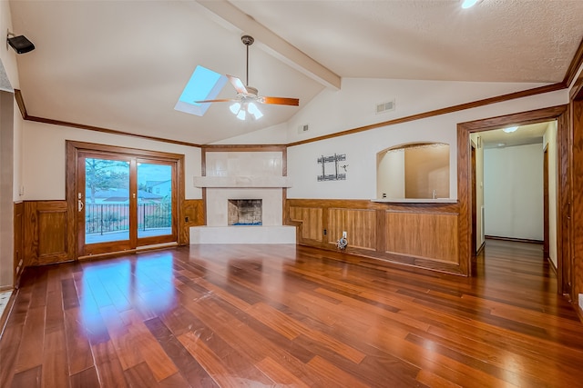 unfurnished living room featuring dark wood-type flooring, crown molding, vaulted ceiling with skylight, and a textured ceiling