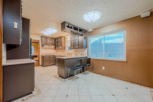 kitchen with kitchen peninsula, decorative backsplash, a breakfast bar area, a textured ceiling, and sink