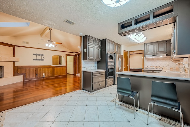 kitchen featuring lofted ceiling, tasteful backsplash, ceiling fan, appliances with stainless steel finishes, and sink