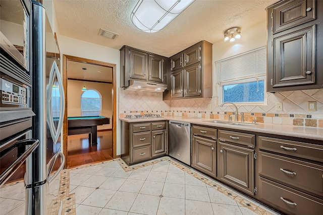 kitchen featuring appliances with stainless steel finishes, a textured ceiling, tasteful backsplash, and a wealth of natural light