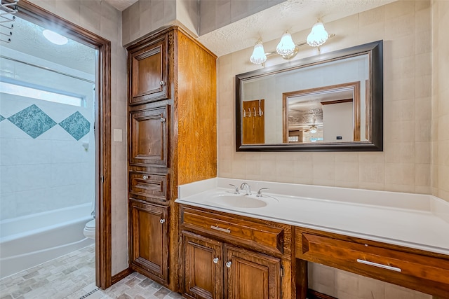 bathroom with vanity, a textured ceiling, toilet, and tile walls