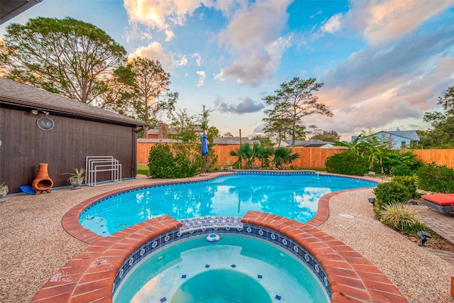 pool at dusk with an in ground hot tub