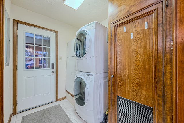 laundry room with light tile patterned flooring and stacked washer / dryer