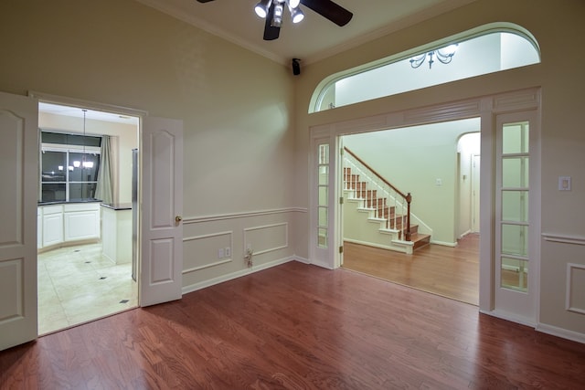 entryway featuring ornamental molding, hardwood / wood-style flooring, a towering ceiling, and ceiling fan