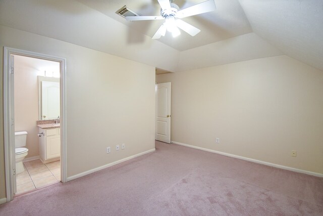 unfurnished bedroom with ensuite bathroom, light carpet, vaulted ceiling, and ceiling fan