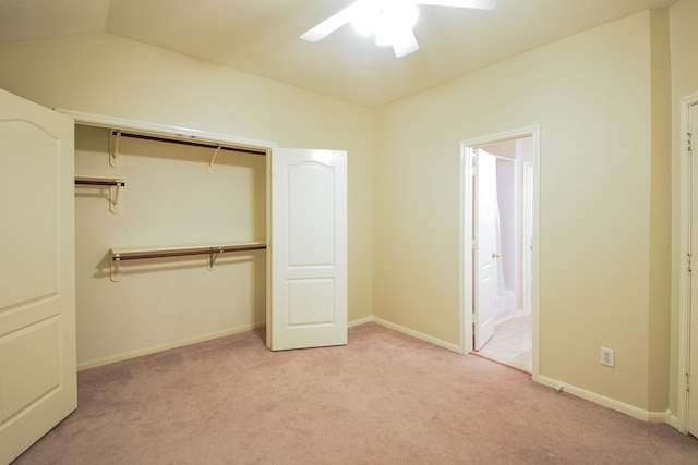 unfurnished bedroom with a closet, vaulted ceiling, light colored carpet, ensuite bathroom, and ceiling fan